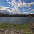 Crater Lake on the Appalachian Trail in New Jersey Blue sky with clouds grassy shoreline with rocks and shrubs